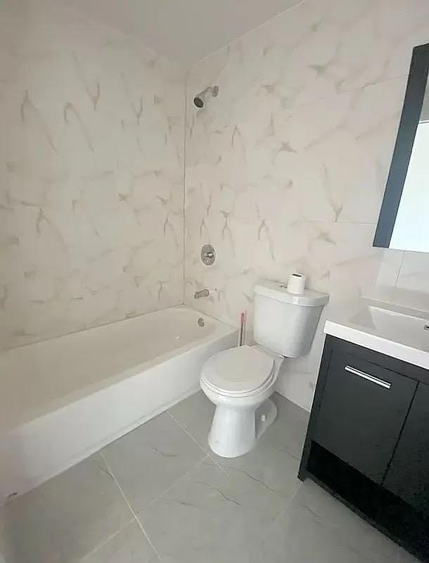 full bathroom with toilet, vanity, tile walls, and tiled shower / bath