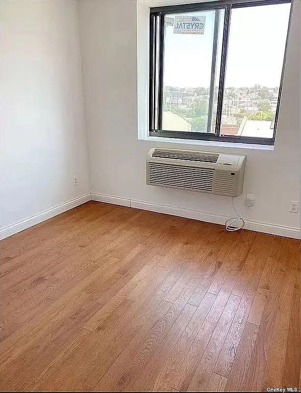 empty room featuring wood-type flooring and a wall mounted air conditioner