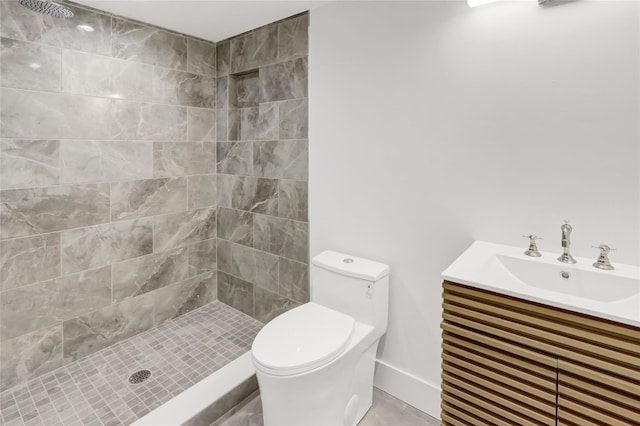 bathroom featuring a tile shower, vanity, and toilet