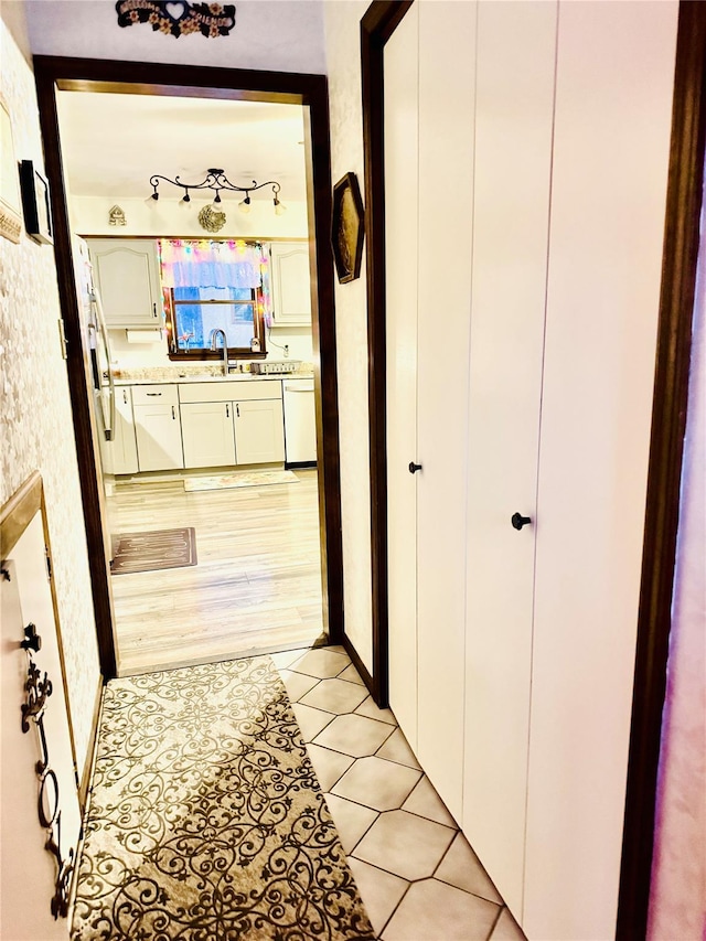 corridor featuring light tile patterned flooring and sink