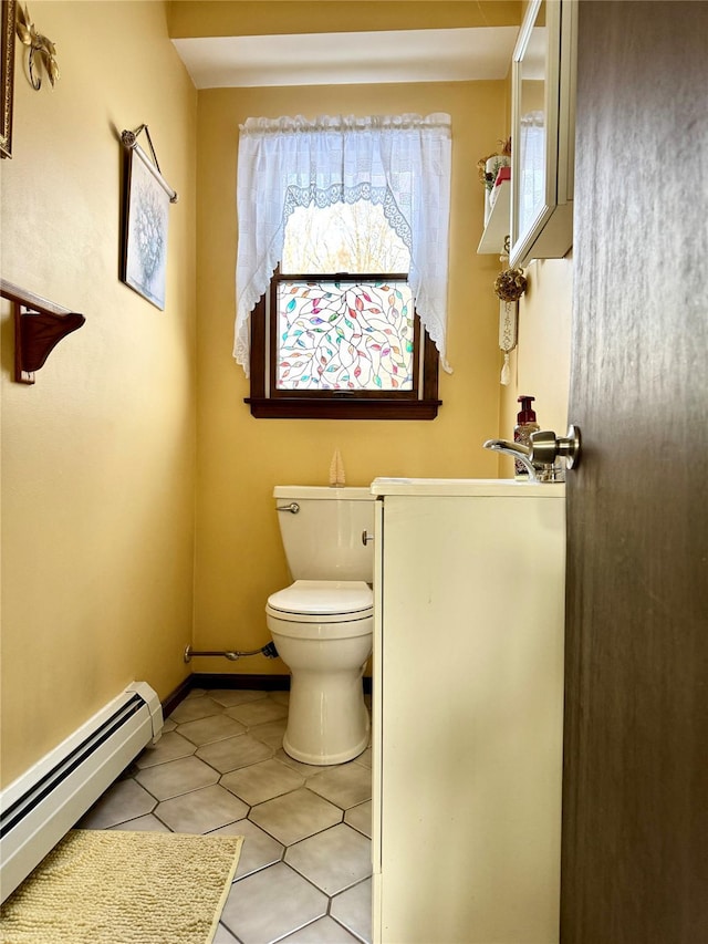 bathroom featuring toilet, sink, a wealth of natural light, and a baseboard heating unit