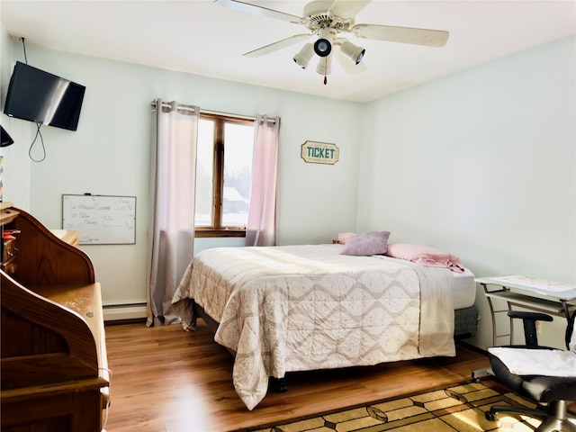 bedroom featuring ceiling fan, light hardwood / wood-style floors, and a baseboard heating unit