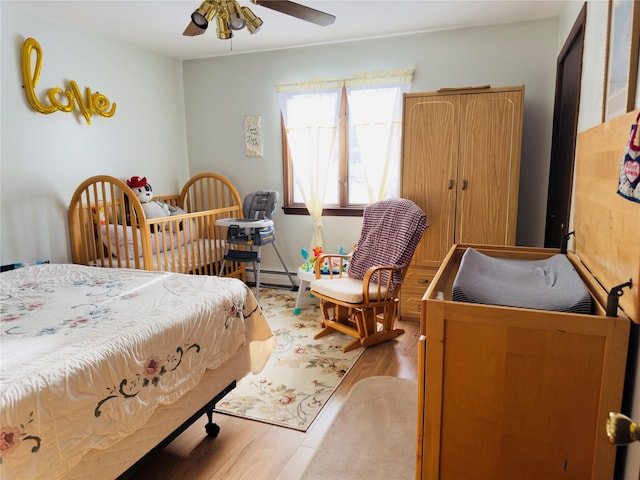 bedroom featuring hardwood / wood-style floors, ceiling fan, and a baseboard heating unit