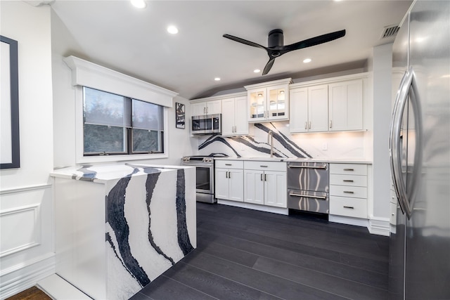 kitchen with ceiling fan, appliances with stainless steel finishes, backsplash, dark wood-type flooring, and white cabinets