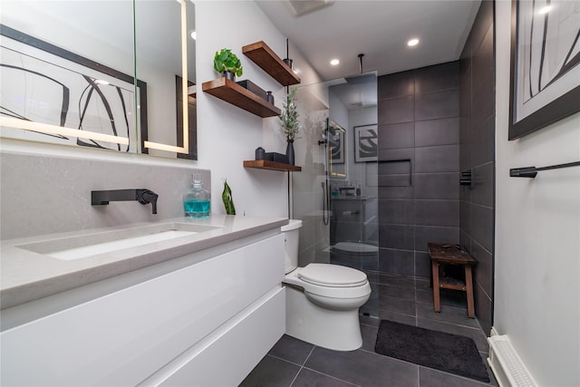 bathroom featuring toilet, tile patterned flooring, a tile shower, and vanity