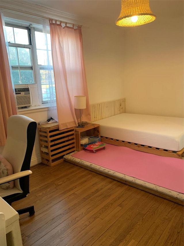 bedroom featuring hardwood / wood-style floors, cooling unit, and ornamental molding