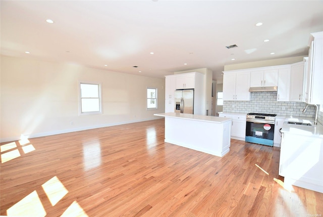 kitchen featuring appliances with stainless steel finishes, tasteful backsplash, sink, a center island, and white cabinetry