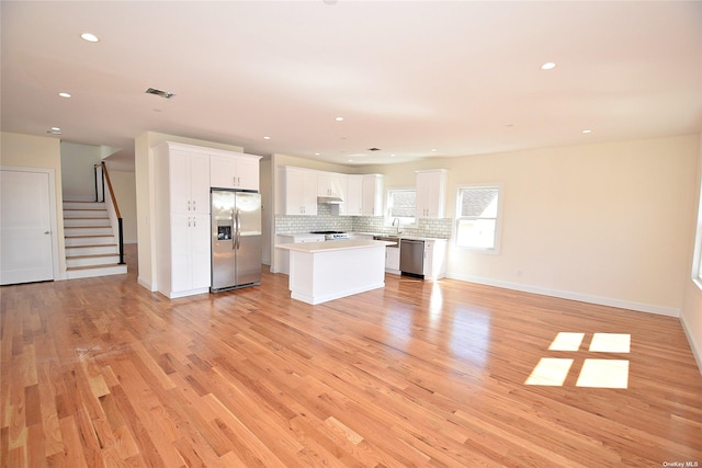 kitchen with a center island, light hardwood / wood-style flooring, decorative backsplash, appliances with stainless steel finishes, and white cabinetry