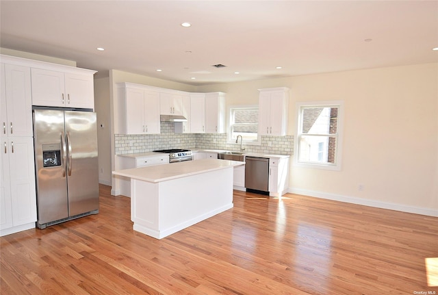 kitchen featuring a center island, white cabinets, sink, light hardwood / wood-style flooring, and appliances with stainless steel finishes