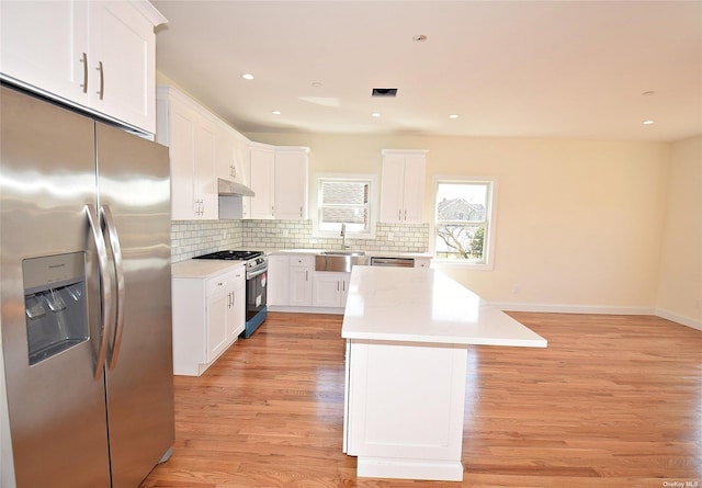 kitchen featuring white cabinets, a kitchen island, appliances with stainless steel finishes, and light hardwood / wood-style flooring