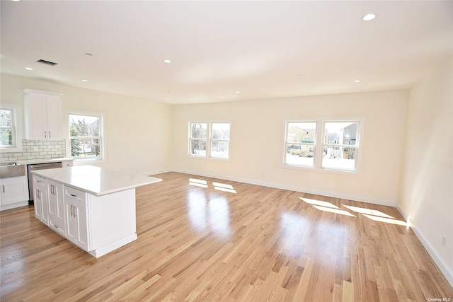 kitchen featuring white cabinets, decorative backsplash, a center island, and light hardwood / wood-style floors