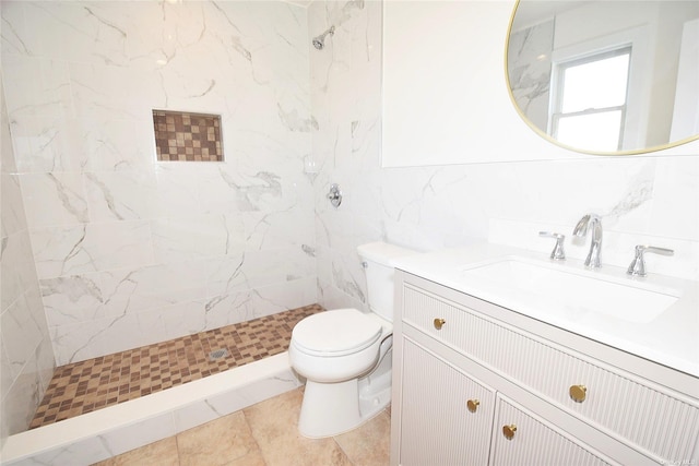 bathroom featuring a tile shower, vanity, tile walls, tile patterned flooring, and toilet