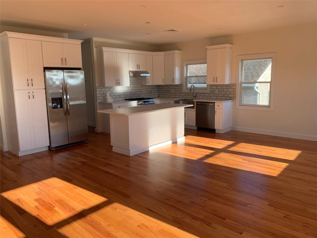 kitchen with white cabinetry, a kitchen island, stainless steel appliances, and light wood-type flooring