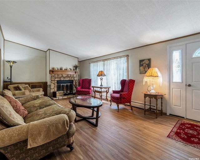 living room featuring vaulted ceiling, a baseboard heating unit, crown molding, hardwood / wood-style flooring, and a fireplace