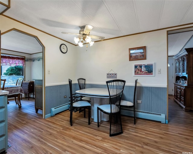 dining space featuring wood-type flooring, a textured ceiling, ceiling fan, and ornamental molding