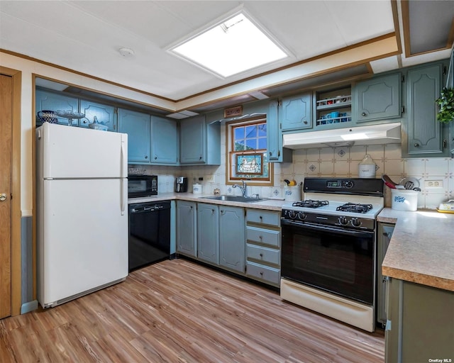 kitchen with decorative backsplash, sink, black appliances, and light wood-type flooring