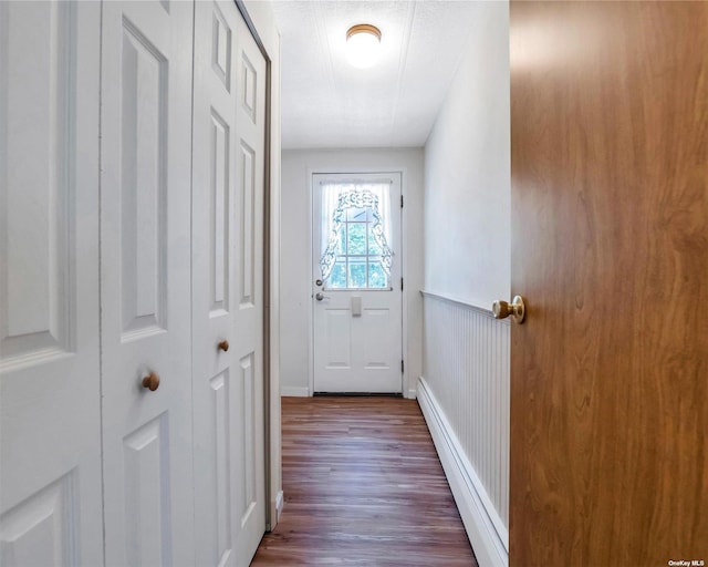 doorway to outside featuring baseboard heating, a textured ceiling, and dark hardwood / wood-style floors