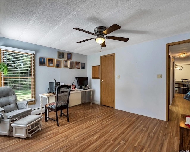 office space with ceiling fan, wood-type flooring, a textured ceiling, and a baseboard heating unit