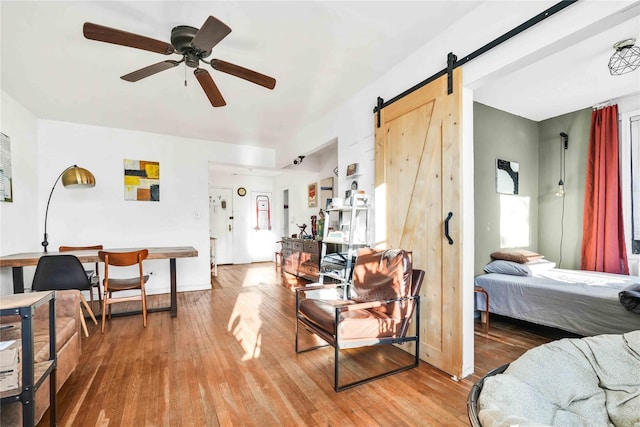 living room with wood-type flooring, a barn door, and ceiling fan