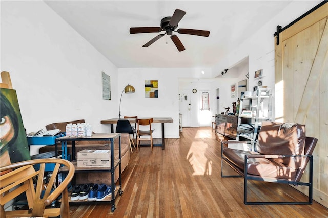 living room featuring a barn door, ceiling fan, and hardwood / wood-style floors