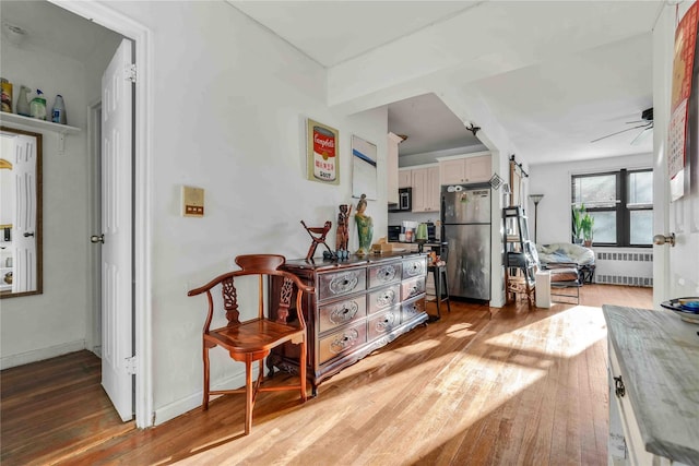 living area featuring wood-type flooring, radiator, and ceiling fan