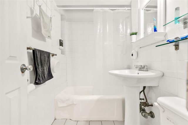 bathroom with tile patterned floors, shower / bath combo, toilet, and tile walls