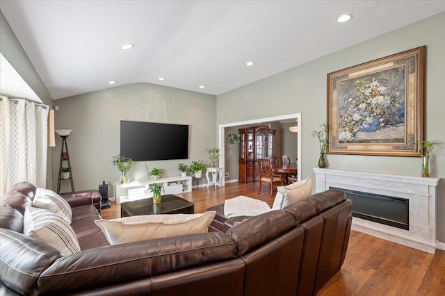 living room with plenty of natural light, a fireplace, wood-type flooring, and lofted ceiling