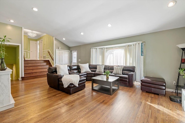 living room with lofted ceiling, a notable chandelier, and light wood-type flooring