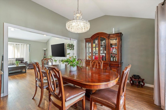 dining room featuring light hardwood / wood-style floors, vaulted ceiling, and a notable chandelier