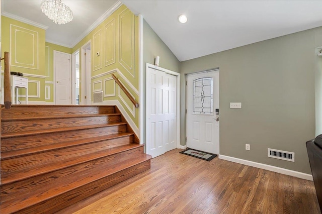 entrance foyer with crown molding, a notable chandelier, and hardwood / wood-style flooring