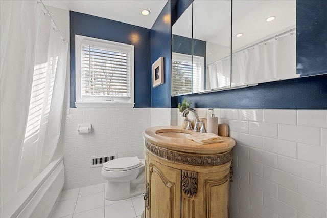 full bathroom with a wealth of natural light, toilet, and tile walls