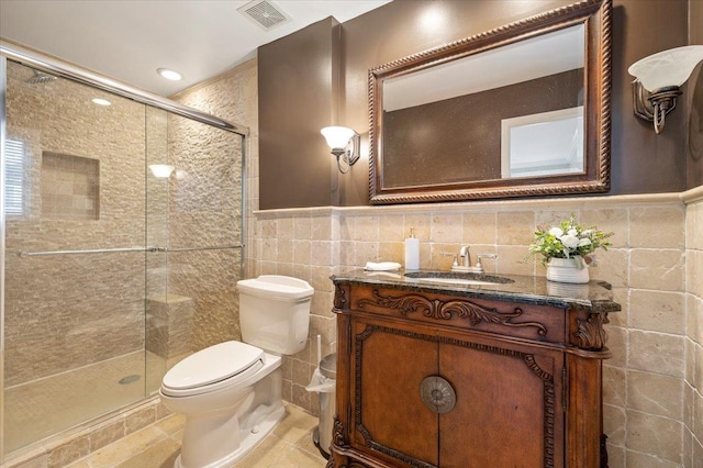 bathroom with walk in shower, vanity, toilet, and tile walls