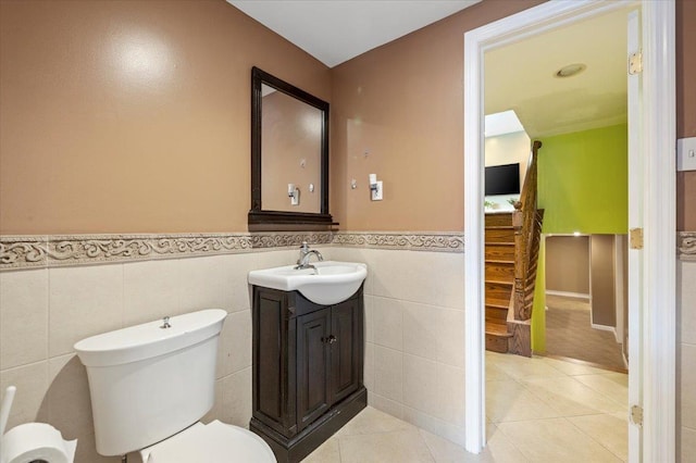 bathroom with tile patterned flooring, vanity, toilet, and tile walls