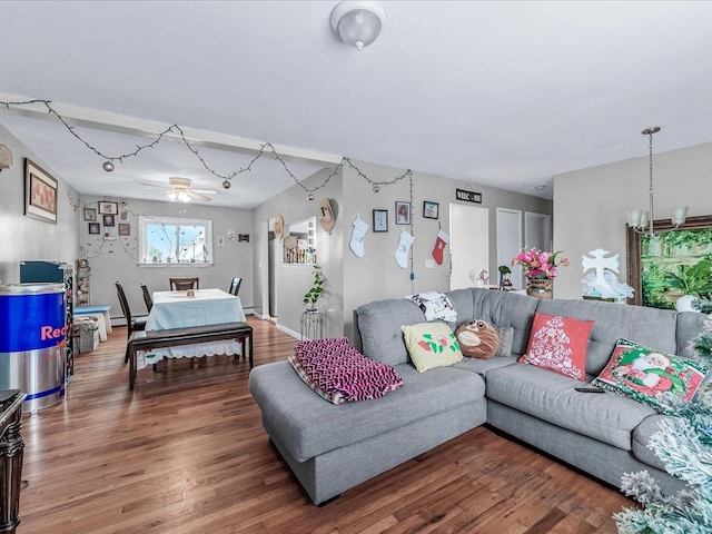 living room featuring ceiling fan with notable chandelier, wood-type flooring, and a baseboard heating unit