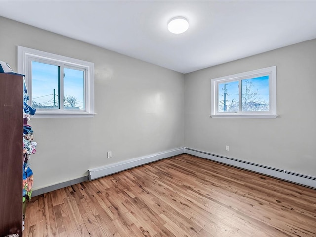 empty room featuring plenty of natural light, light hardwood / wood-style floors, and a baseboard radiator