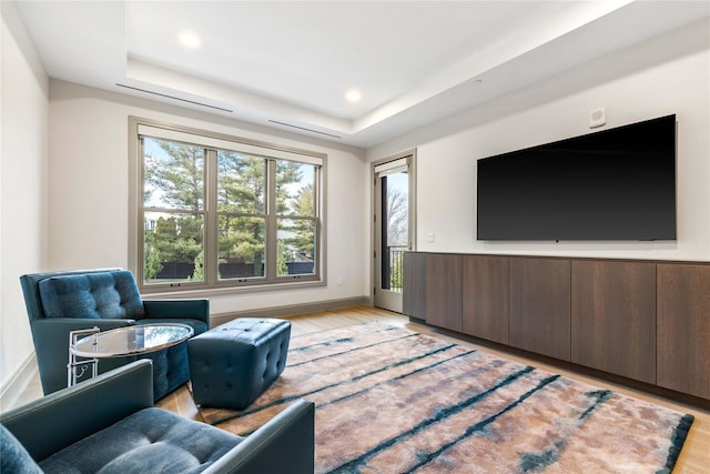 living room with a raised ceiling and light hardwood / wood-style floors