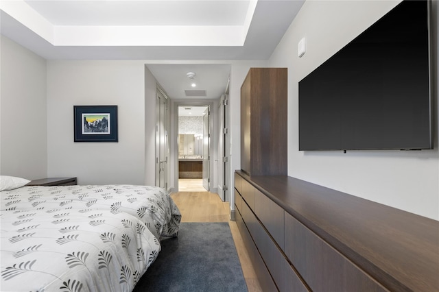 bedroom featuring light hardwood / wood-style floors and ensuite bath