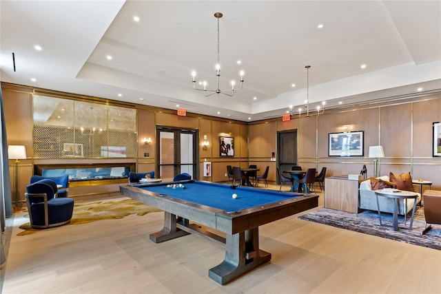 rec room featuring a tray ceiling, a chandelier, light wood-type flooring, and pool table