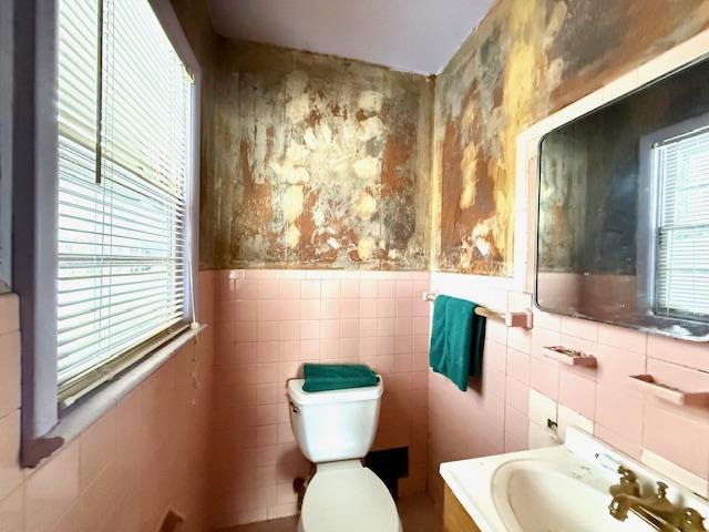 bathroom featuring vanity, toilet, and tile walls