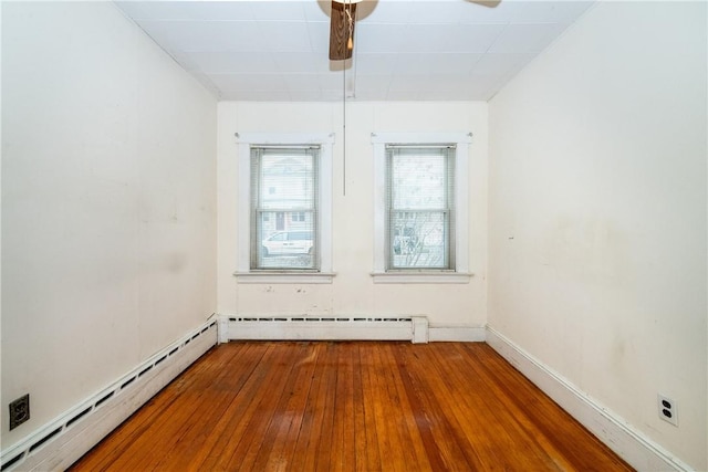 spare room with hardwood / wood-style flooring, baseboard heating, and ceiling fan