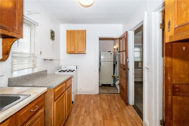 kitchen with gas range, sink, light hardwood / wood-style flooring, a baseboard heating unit, and white refrigerator