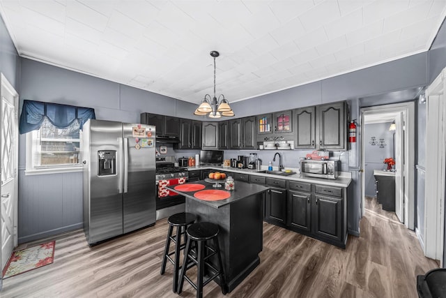 kitchen featuring appliances with stainless steel finishes, sink, hardwood / wood-style flooring, a chandelier, and a center island