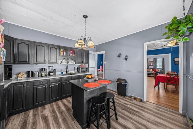 kitchen featuring dark wood-type flooring, sink, decorative light fixtures, a center island, and a breakfast bar area