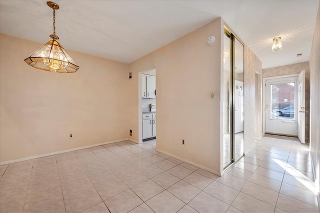 unfurnished room with an inviting chandelier and light tile patterned flooring