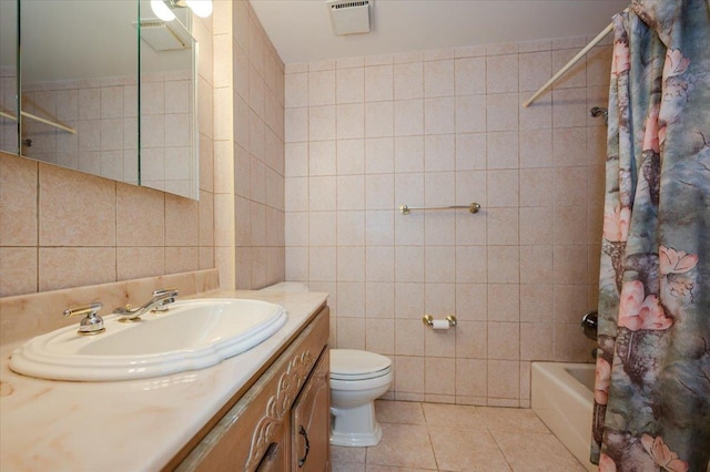 full bathroom featuring toilet, tile patterned flooring, shower / bath combo with shower curtain, tile walls, and vanity