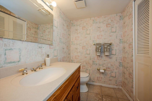 bathroom with toilet, vanity, and tile patterned floors