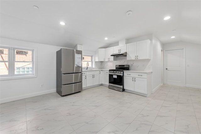 kitchen with appliances with stainless steel finishes, tasteful backsplash, vaulted ceiling, sink, and white cabinets