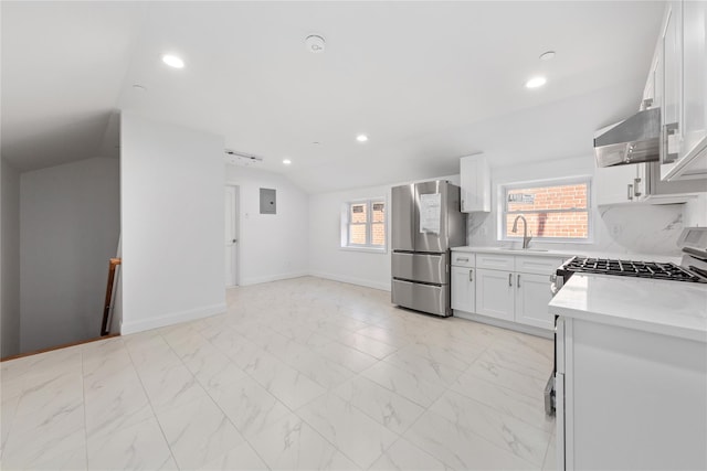 kitchen featuring lofted ceiling, exhaust hood, white cabinets, decorative backsplash, and stainless steel fridge