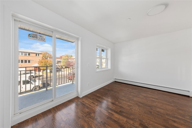 empty room featuring baseboard heating and dark wood-type flooring