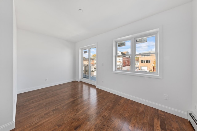 spare room with baseboard heating and dark hardwood / wood-style floors